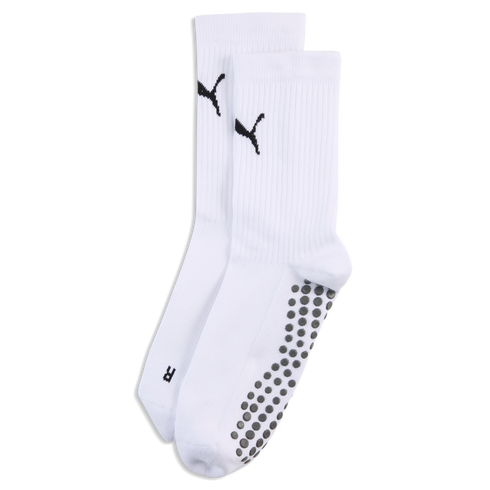 White Puma crew socks with black logos on the ankles and grey non-slip grippers on the soles, against a black background.