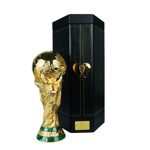 The gold FIFA World Cup trophy stands next to its black carrying case with gold hardware, against a solid black background.