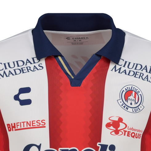Close-up of an Atlético San Luis soccer jersey with red and white vertical stripes, a navy collar, and logos for Charly and several sponsors.