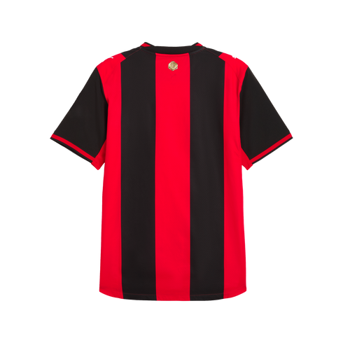 Back view of a red and black vertically striped soccer jersey with short sleeves and a small gold emblem below the collar, set against a plain white background.