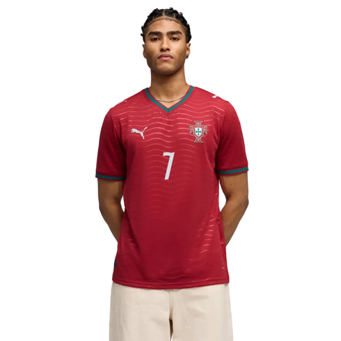 A man wearing a red Morocco national team soccer jersey with the number 7, standing against a black background.