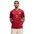 A man wearing a red Morocco national team soccer jersey with the number 7, standing against a black background.