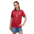 A young woman with red hair wears a red Portugal soccer jersey with number 7 and a denim skirt, posing against a black background.