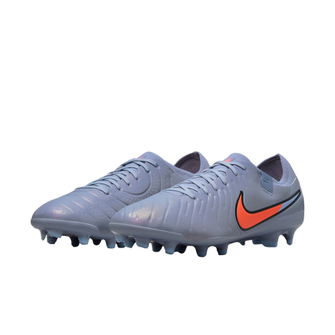 Grey iridescent Nike soccer cleats with a bright orange swoosh on a black background.