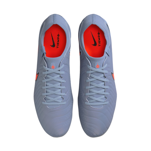 Top-down view of a pair of light blue Nike Tiempo soccer cleats with bright orange insoles and black branding, set against a solid black background.