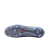 Bottom of a grey Nike soccer cleat with light blue studs and an orange swoosh on a black background. Translucent soleplate features circular traction patterns.