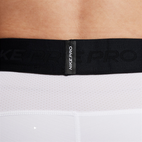 Close-up of a black Nike Pro elastic waistband on white mesh performance shorts.