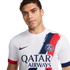 A man posing in a white Nike Paris Saint-Germain (PSG) away jersey featuring a blue and red brushstroke design and the Qatar Airways sponsor logo.