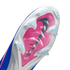 Underside of a blue and white Nike soccer cleat with a pink soleplate, a large black Nike swoosh, and clear triangular studs against a black background.