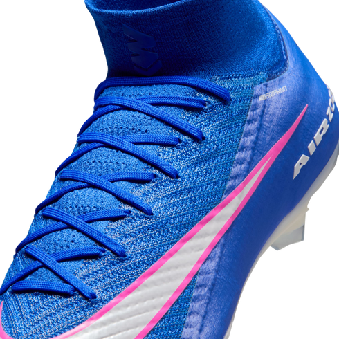 A close-up of a blue Nike soccer cleat with pink and white accents, blue laces, and a textured upper against a black background.