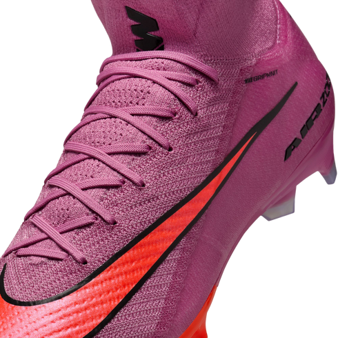Close-up of a pink Nike soccer cleat with a textured knit upper, bright orange swoosh, and pink laces.