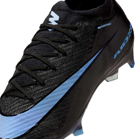 A close-up of a black Nike soccer cleat featuring a light blue swoosh, textured Gripknit upper, and light blue studs.
