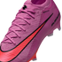 Close-up of a pink Nike soccer cleat featuring a textured Gripknit upper, matching laces, and a bold red swoosh with black outline against a dark background.
