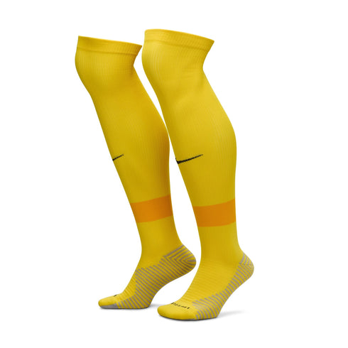 Pair of yellow Nike soccer socks with an orange calf stripe and grey-striped foot sections, standing upright against a white background.