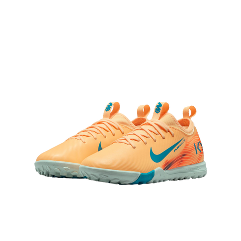 A pair of peach-colored Nike Air Zoom turf soccer shoes with teal accents and a light grey studded sole.