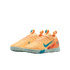 A pair of peach-colored Nike Air Zoom turf soccer shoes with teal accents and a light grey studded sole.