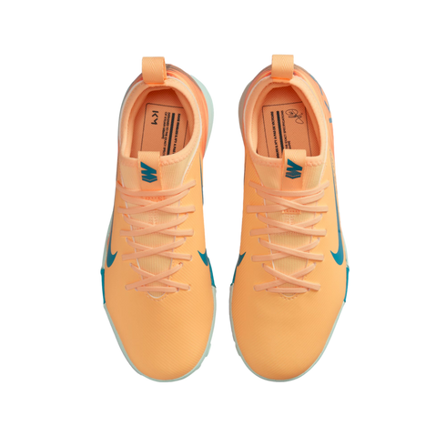 Top-down view of bright orange Nike Mercurial soccer shoes with teal accents and Kylian Mbappé branding against a black background.