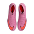 Top-down view of pink Nike Mercurial soccer cleats with bright orange swooshes and matching laces, set against a solid black background.
