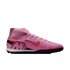 Pink Nike soccer shoe with a high-top collar, orange swoosh, and large "M" logo on the heel, set against a black background.