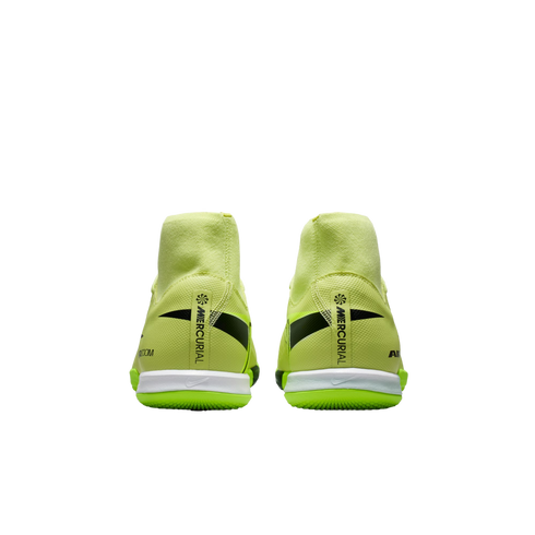 Rear view of neon yellow Nike Mercurial indoor soccer shoes featuring high-top collars and black branding on the heels, set against a black background.