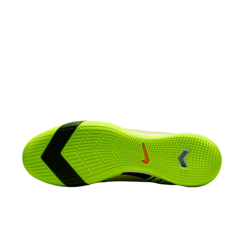 Sole of a neon yellow Nike indoor soccer shoe with a black diagonal stripe and textured grip pattern, set against a black background.