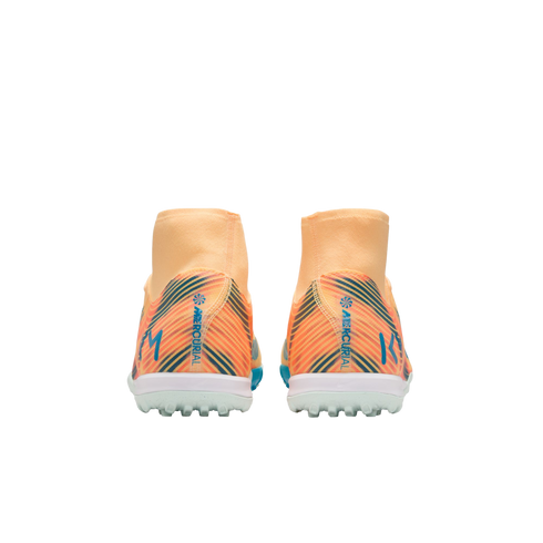 Rear view of orange and peach Nike Mercurial soccer shoes featuring a sock collar, blue accents, and white turf soles, set against a black background.