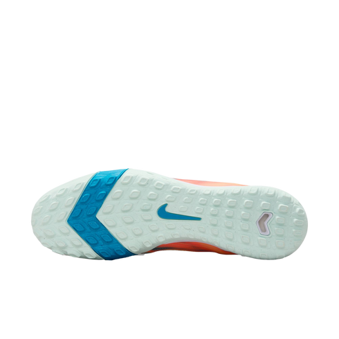 Sole of a Nike soccer shoe with a mint green and blue textured tread pattern and a blue swoosh in the center, set against a black background.