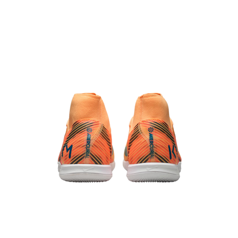 Rear view of orange Nike Mercurial indoor soccer shoes featuring black diagonal stripes, white soles, and high collars against a black background.