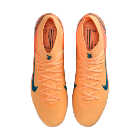 Top-down view of a pair of bright orange Nike soccer cleats with teal swooshes and laces, isolated on a black background.