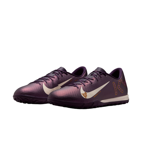 A pair of iridescent purple Nike turf soccer shoes featuring white swooshes and gold graphic details.