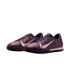 A pair of iridescent purple Nike turf soccer shoes featuring white swooshes and gold graphic details.