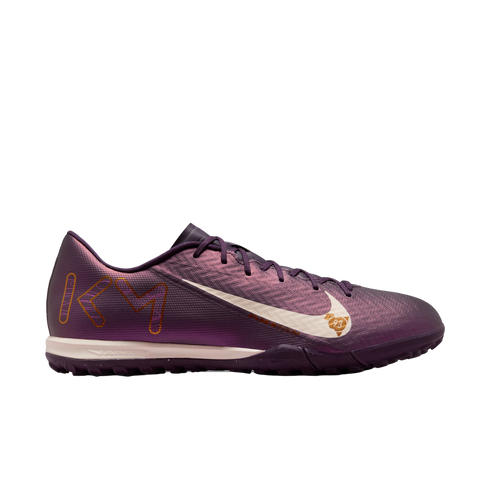 Side view of an iridescent purple Nike Mercurial turf soccer shoe featuring a large white Swoosh and gold "KM" branding on the heel.