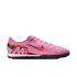 Side profile of a pink Nike Mercurial soccer shoe with orange accents and a black turf sole against a solid black background.