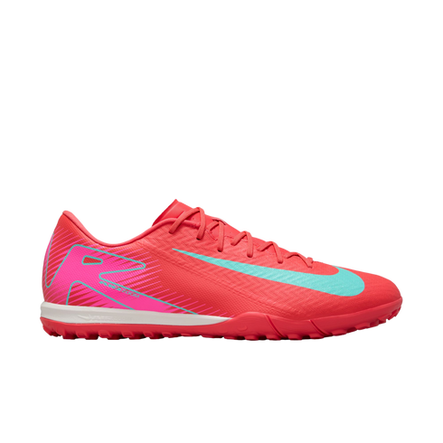 A profile view of a vibrant pink Nike turf soccer shoe featuring a light blue swoosh, white midsole, and pink studded outsole, set against a plain white background.
