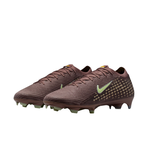 A pair of dark reddish-brown Nike soccer cleats with light green swooshes and studs, featuring a golden dot pattern, against a solid black background.