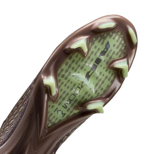 Close-up of the sole of a brown soccer cleat with pale green studs and a translucent green central panel featuring "AIR ZOOM" branding against a black background.