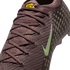 Close-up of a mauve Nike soccer cleat with a knit texture, lime green swoosh, and yellow KM logo on the tongue. Gold dot patterns are visible on the side.