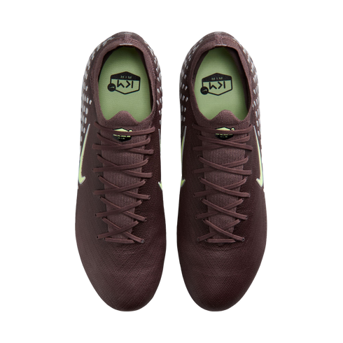 Overhead view of a pair of dark maroon Nike soccer cleats with light green accents and insoles, set against a black background.