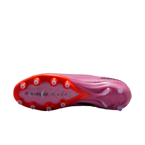 The bottom of a pink and orange soccer cleat against a black background, showing the stud pattern and "AIR ZOOM" branding on the soleplate.