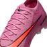 Close-up of a pink Nike soccer cleat featuring a textured knit upper, matching pink laces, and a vibrant orange swoosh logo with black trim.