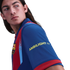 A person with long hair wearing an FC Barcelona soccer jersey with "AMBILIGHT tv" on the sleeve, looking back over their shoulder against a black background.