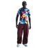 Man wearing a patterned FC Barcelona jersey, maroon baggy pants, and light blue sneakers against a black background.