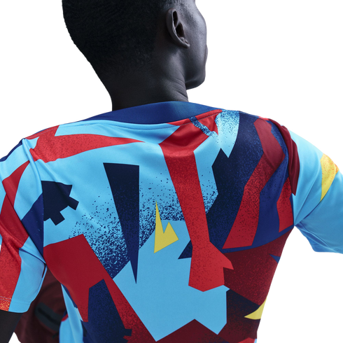 Back view of a person wearing a colorful sports jersey with bold geometric patterns in blue, red, and yellow against a black background.