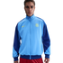 A man models a light and dark blue Nike FC Barcelona track jacket with a yellow club crest, posed against a solid black background.