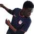 A Black man in a navy USA soccer jersey with red and blue pinstripes, featuring the Nike logo and team crest. He is in a dynamic pose against a white background.