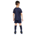 Rear view of a boy in a navy blue USA soccer kit with red and blue pinstripes, matching shorts with red trim, navy socks labeled "USA," and black soccer cleats.