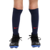 A close-up of a person's legs wearing navy blue Nike soccer socks with red swooshes and black cleats with blue soles against a white background.