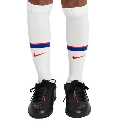Person wearing white Nike soccer socks with red and blue stripes and black Nike soccer shoes with red-outlined logos.