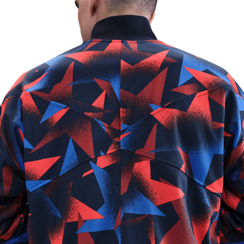 Rear view of a person wearing a jacket with a graphic red, blue, and black geometric pattern. The jacket has a high black collar and visible back seams.