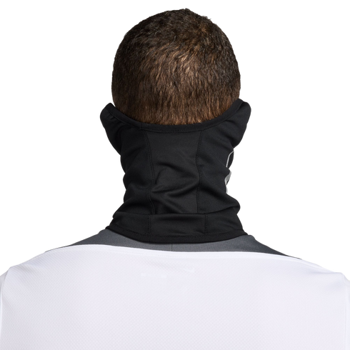 Back view of a person with short brown hair wearing a black neck gaiter and a white jersey against a black background.
